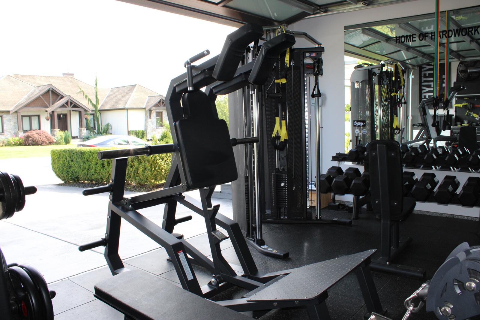 Plate-loaded shoulder press with garage door open to the street — Abbotsford garage gym