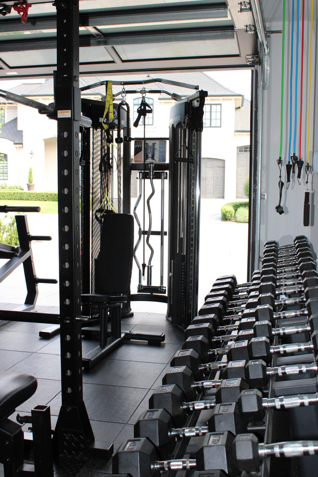 Power rack and full dumbbell rack with natural light through the open garage door — Abbotsford garage gym build