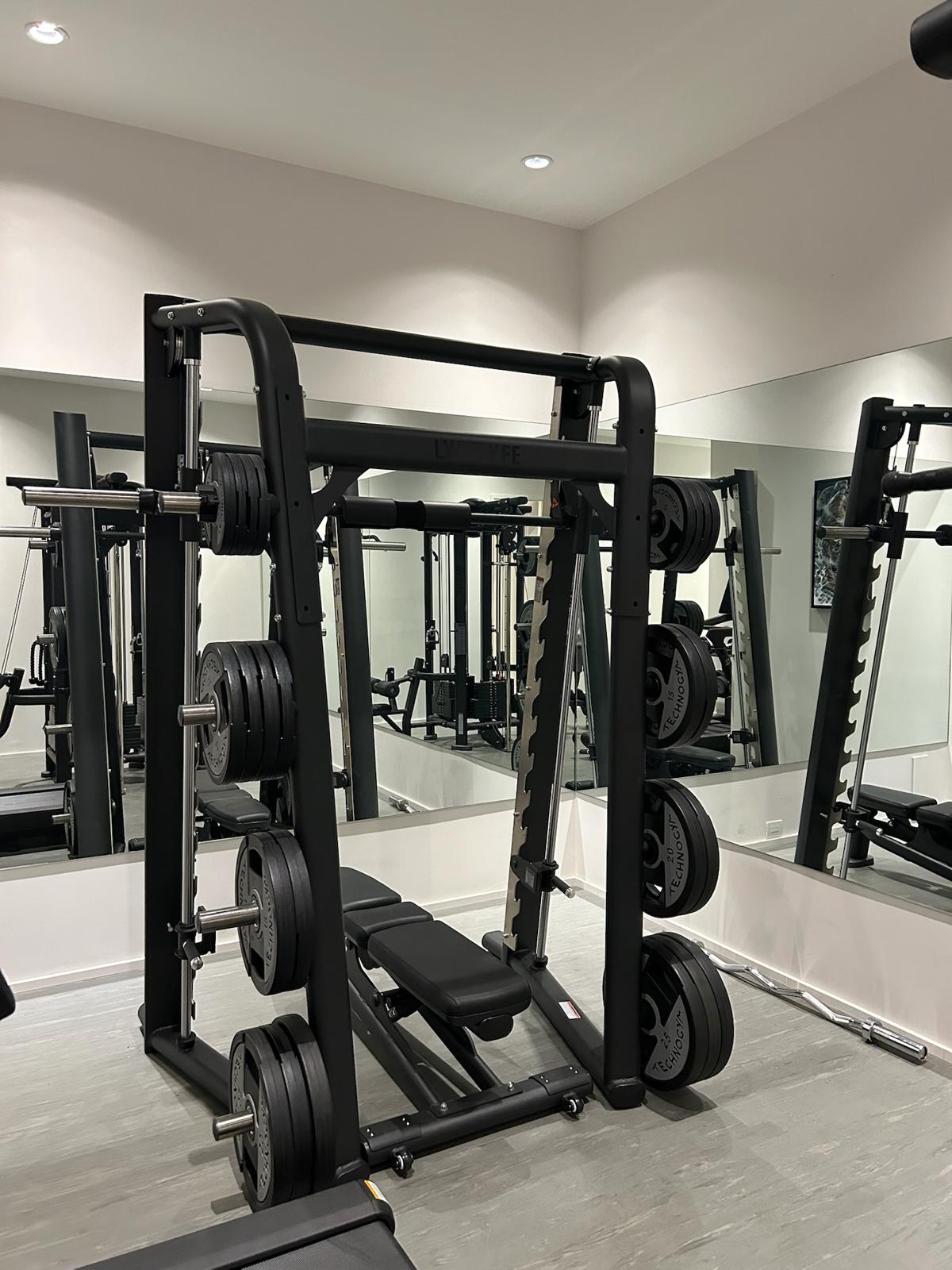 Smith machine loaded with weight plates and an adjustable bench in the Kelowna home gym build.