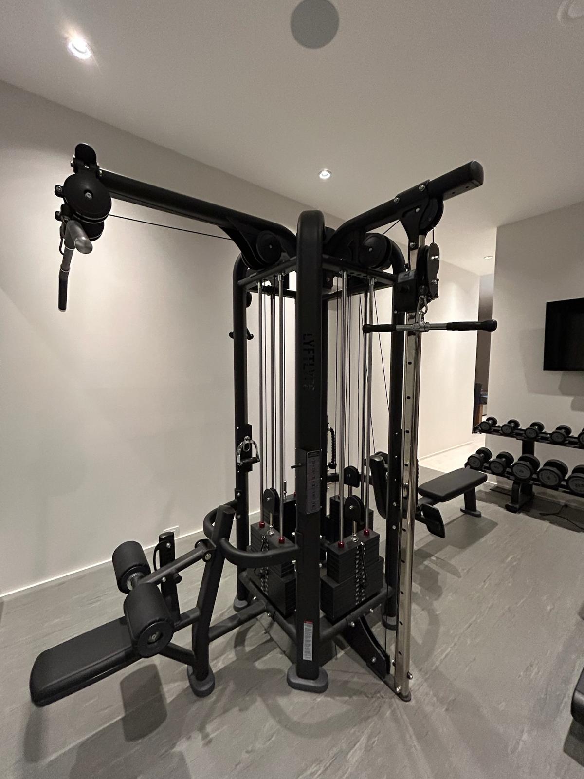 LYFTL 4-station multi-functional cable trainer with leg extension attachment and dumbbell rack in the Kelowna home gym.