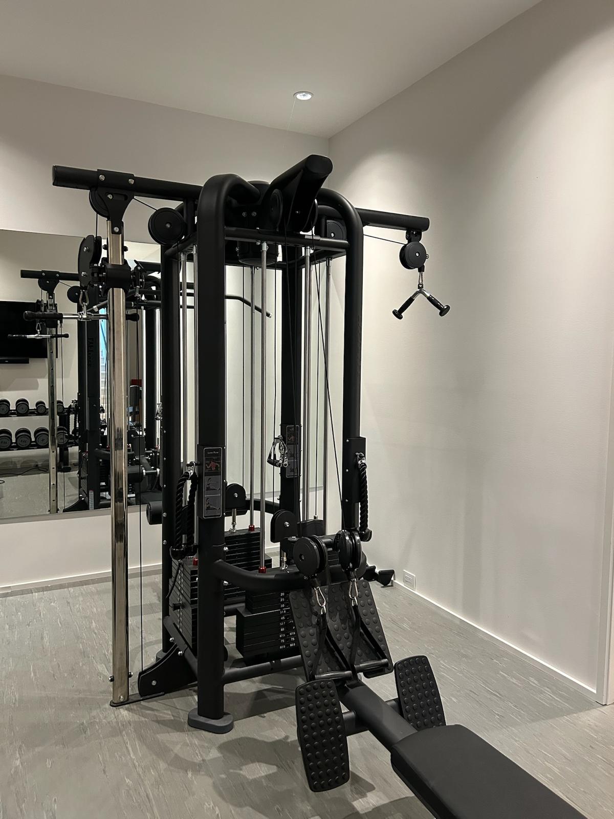 Multi-station cable trainer with weight stack, decline situp bench, and overhead cable pulley in the Kelowna home gym.